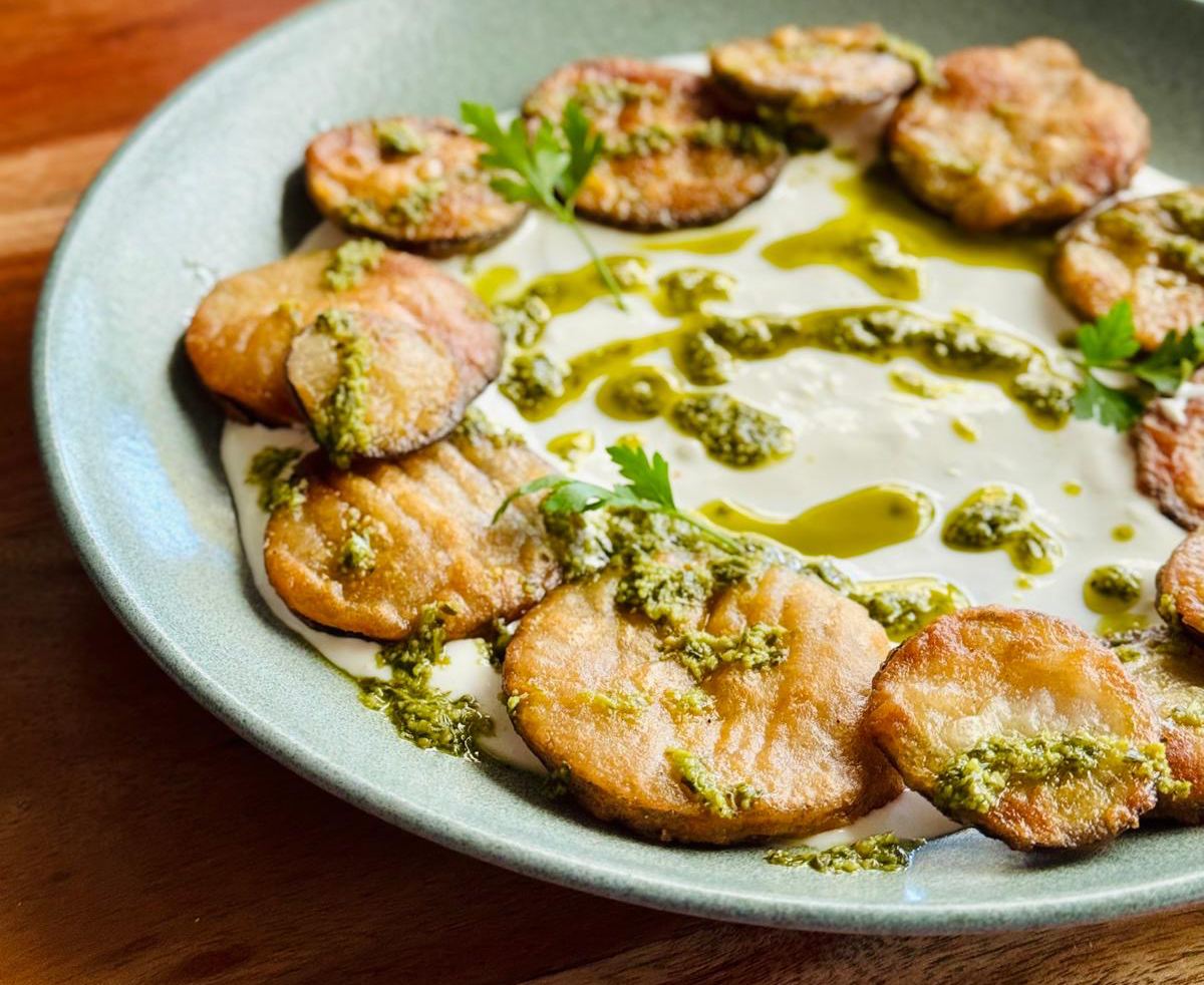 Berenjenas rebozadas sobre crema de queso fresco y pesto verde, comida vegetariana en restaurante Madreselva Tapas Sevilla