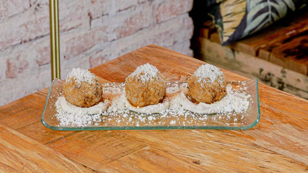 Arancini de ibéricos sobre salsa carbonara en restaurante Madreselva Tapas Sevilla